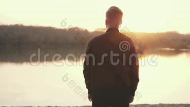 惊讶的情绪男人看着镜头。 日落时海滩上一个英俊的年轻人的肖像。 慢慢慢慢